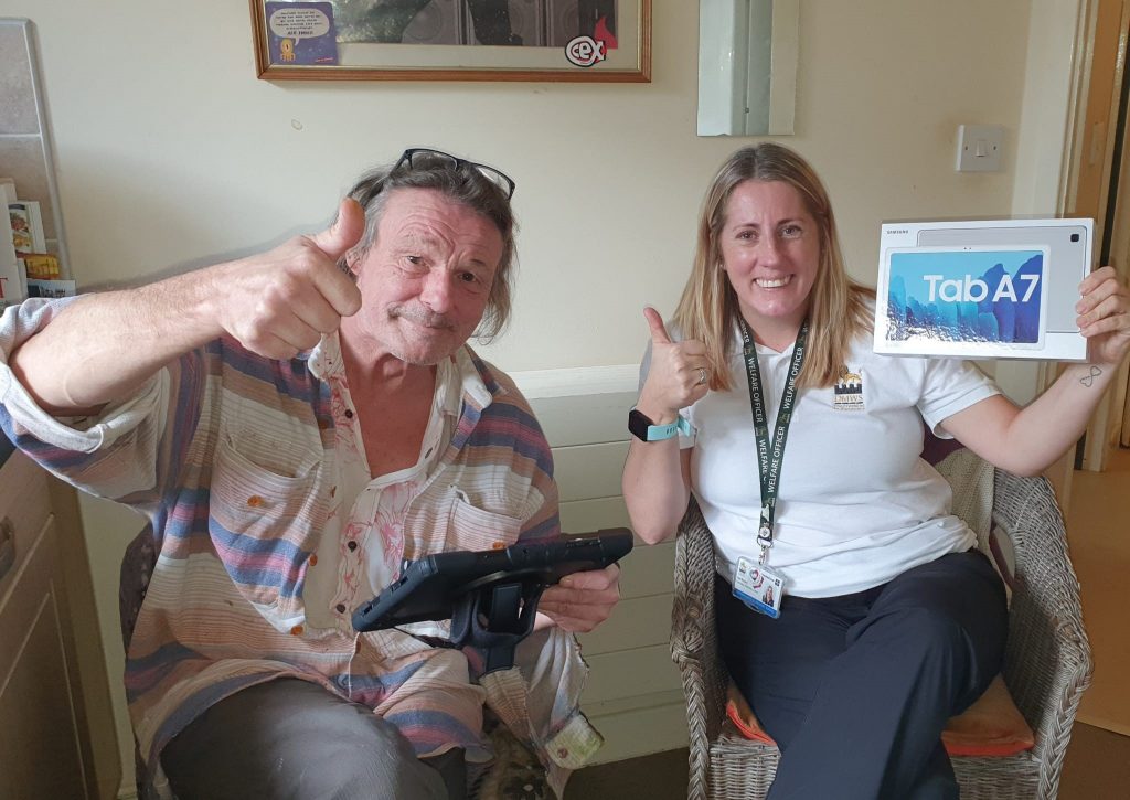 DMWS Welfare Officer Lee Bayley and Veteran Service User smiling to camera holding tablet as part of technology initiative for isolated veterans in Herefordshire.