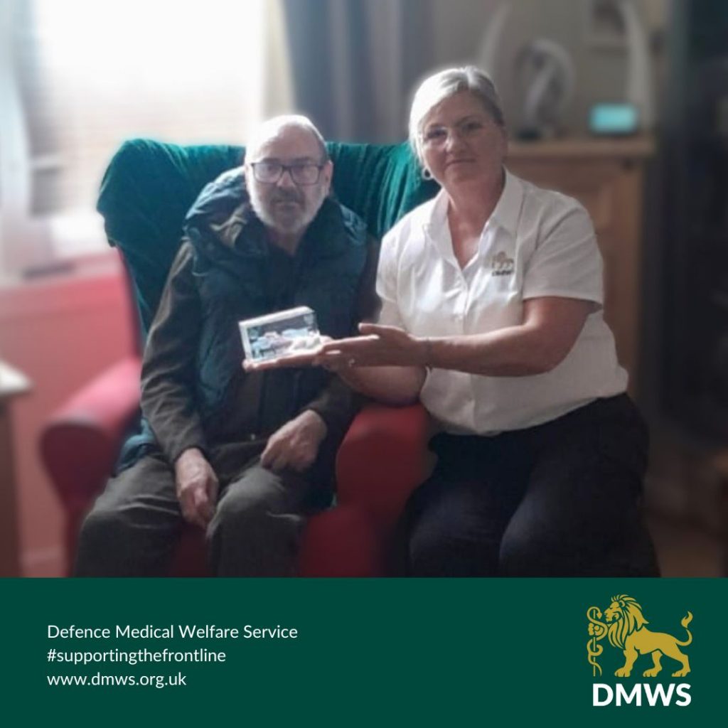 Image shows Kevin, a man sitting down, next to Sam, a DMWS welfare officer, also sitting down. Both smiling at the camera. Green panel along the bottom with DMWS logo in right hand side and text on left which reads 'Defence Medical Welfare Service. #supportingthefrontline - www.dmws.org.uk' 